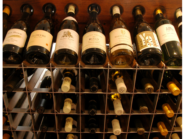 Wine wall with bottles displayed label-out above a grid of Fine Wine Racks in dark wood and aluminum