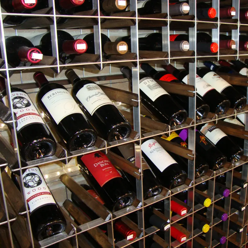 Close-up of modular commercial wine rack cells with stained wood shelving and angled display bottles at The PRIDE Stores