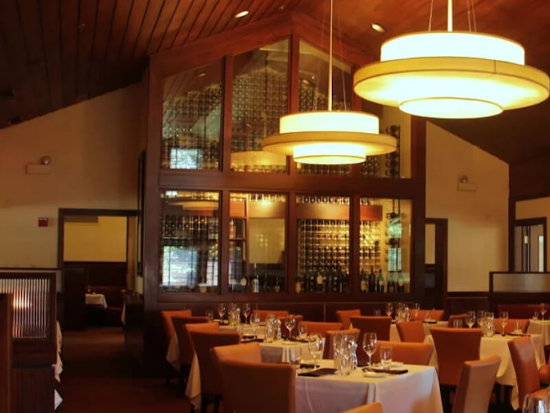 Floor-to-ceiling wine rack wall with polished aluminum framing behind leather booth seating at Sullivan's Steakhouse in Lincolnshire, Illinois