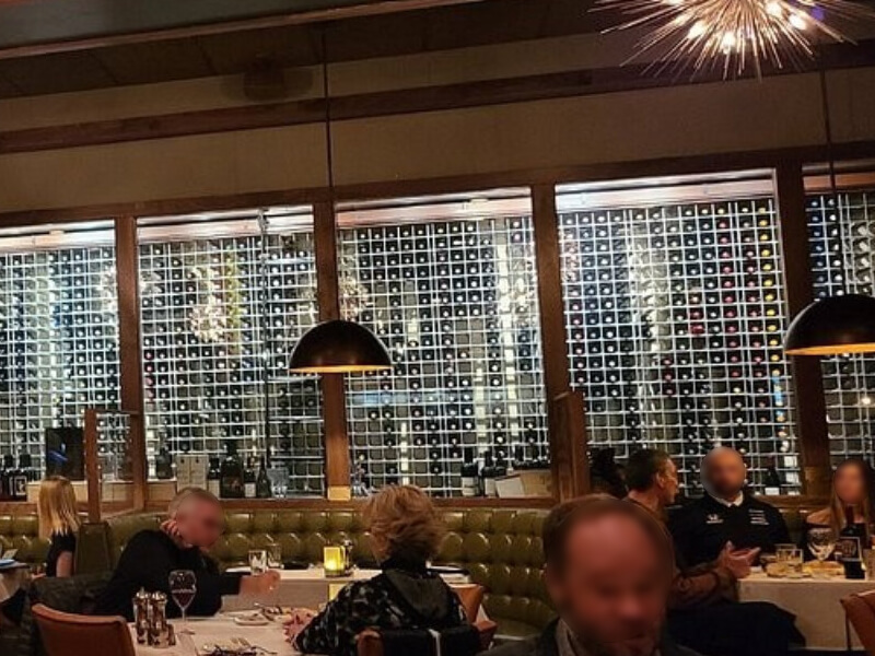 Full-height aluminum-framed wine rack system with polished surfaces reflecting ambient light at Sullivan's Steakhouse in Indianapolis, Indiana