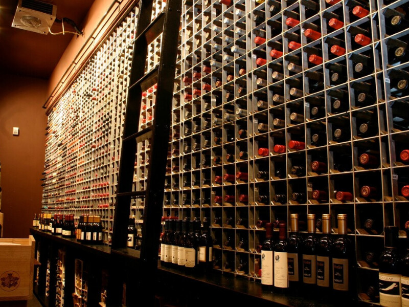 Close-up of aluminum-framed wine rack display with dome pendant lighting and precise bottle positioning at Sullivan's Steakhouse in Omaha, Nebraska