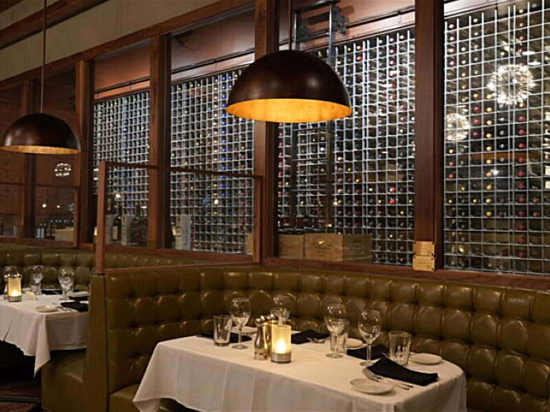 Two-story dining room with floor-to-ceiling wine wall as the architectural focal point at a Sullivan's Steakhouse location