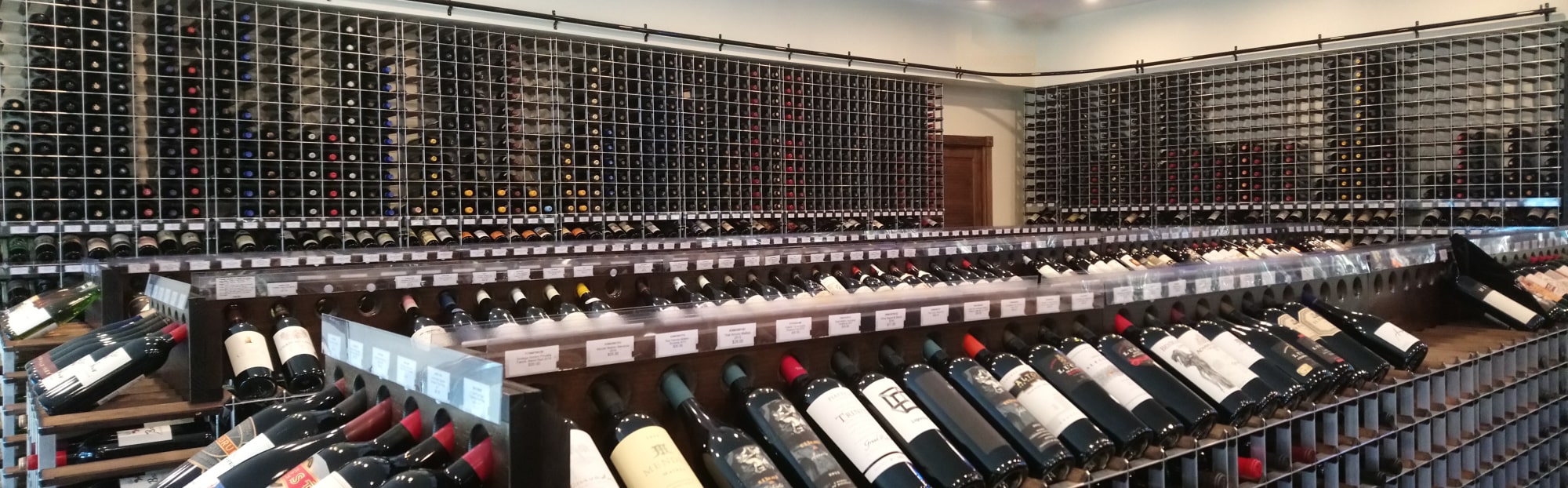 A retail store displaying an array of wine rack options, including wall racks, two-sided aisle racks, and end caps at the end of each aisle