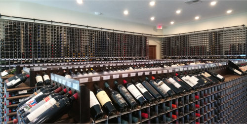 A retail store displaying an array of wine rack options, including wall racks, two-sided aisle racks, and end caps at the end of each aisle